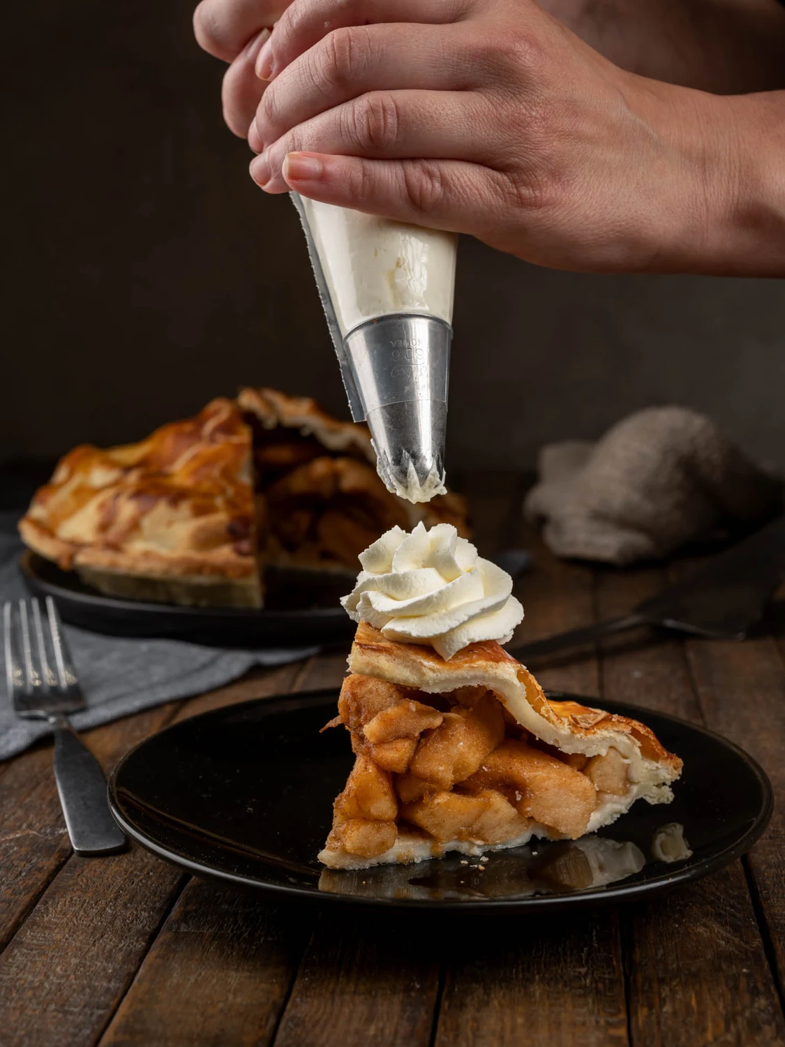 Apple pie slice topped with whipped cream