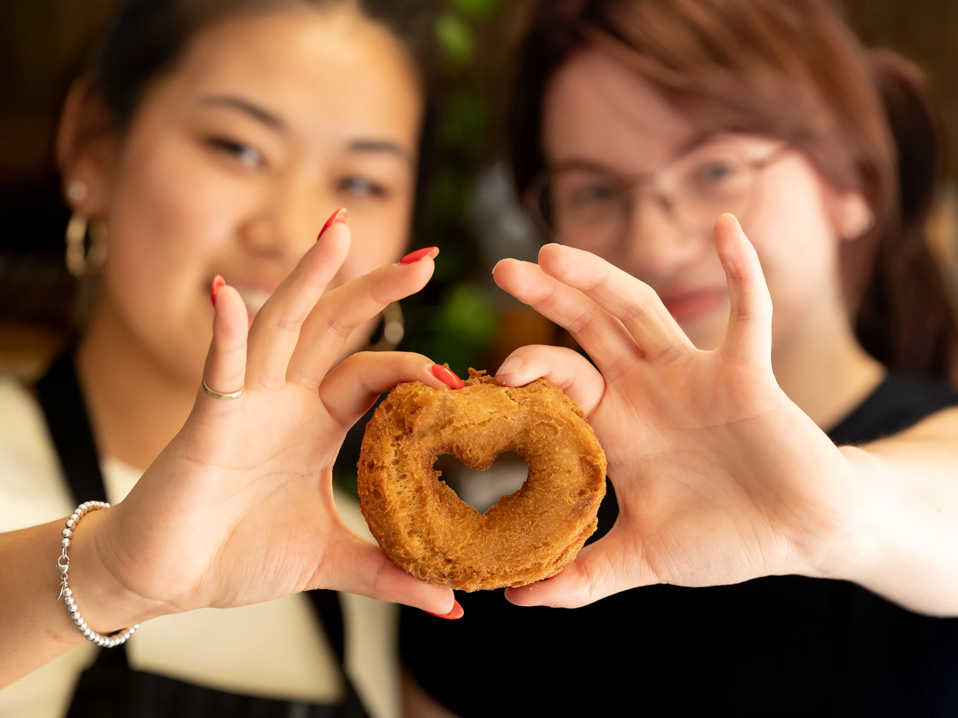 Two guests holding a heart-shaped donut at Crosby Bakery