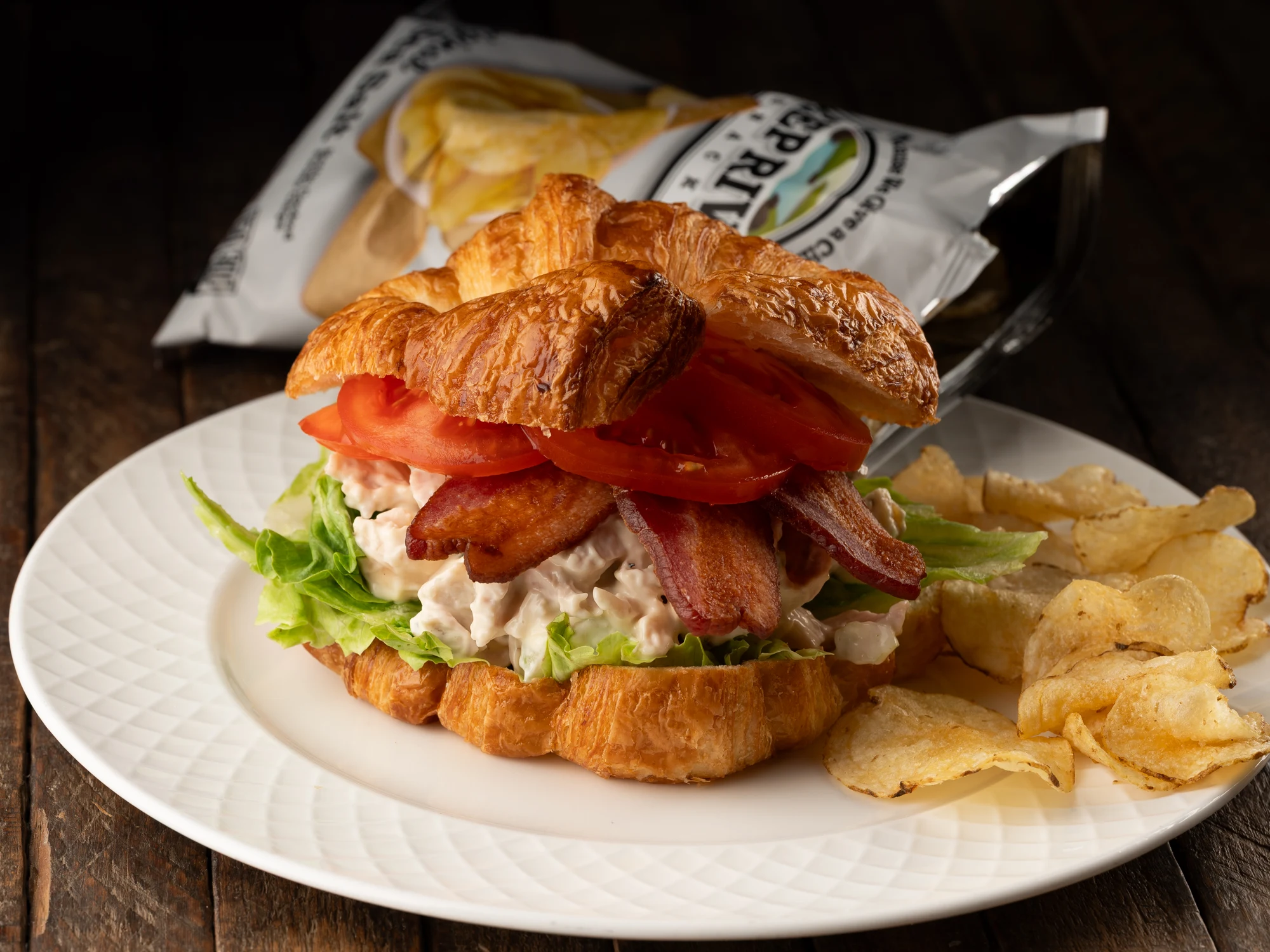 Chicken salad on a croissant with bacon, lettuce and tomato
